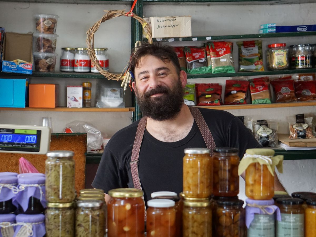 A shopkeeper standing behind shelves of homemade preserves